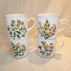 three coffee mugs decorated with wildflowers and leaves on white, blue, yellow or pink stripes