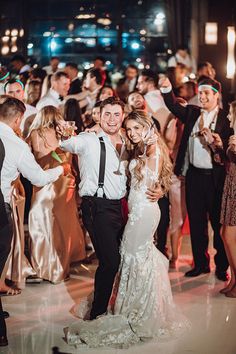 a bride and groom dance together at their wedding reception in front of a large group of people