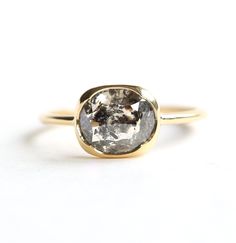 a gold ring with an oval cut diamond in the center, on a white background