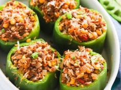 green peppers stuffed with meat and rice in a white dish on a blue table cloth