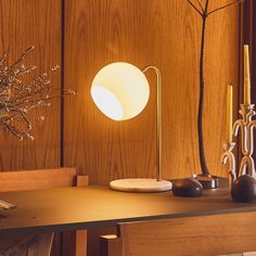 a table with two vases and a lamp on it next to a wooden wall