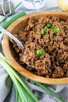 the best crock pot taco meat is in a wooden bowl with green onions