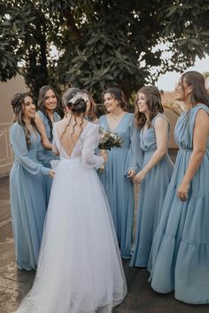 a group of women standing next to each other wearing blue dresses and holding bouquets