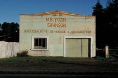 an old building that has been painted white and rusted out with writing on it