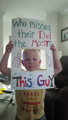 a young boy holding up a sign that says who missed their dad the most?