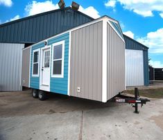 a small blue and white trailer parked in front of a building with a sky background