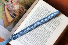 an open book sitting on top of a table next to a blue crochet bracelet