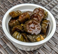 a white bowl filled with stuffed olives sitting on top of a woven table cloth