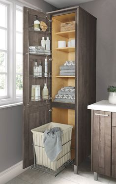 an open cabinet filled with lots of items in a bathroom next to a sink and window