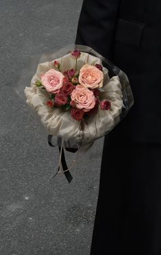 a person holding a bouquet of roses in their hand on the street with other people