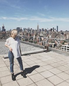 a woman standing on top of a roof looking down at the cityscape behind her