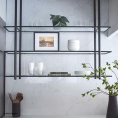 the shelves in this kitchen are filled with dishes and vases, along with plants