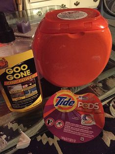 an orange container sitting on top of a glass table next to a bottle of cleaner