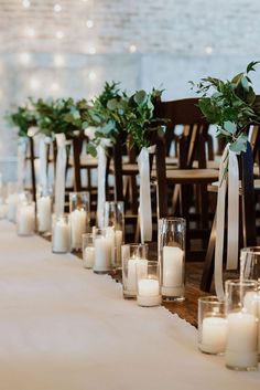 a row of chairs with candles and greenery on them