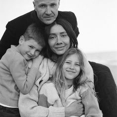 an older man and two young children are posing for a black and white photo with their arms around each other