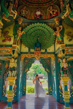 a woman in a white dress standing under an ornate archway