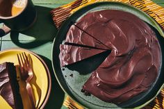 a chocolate cake sitting on top of a green plate next to a cup and fork