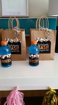 three bags with blue bottles on them sitting on a table next to pink streamers