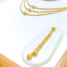 This Shimmering Triple Lara 22k Gold Set, weighing 22.0 grams, exudes timeless elegance and refined style. Crafted from the finest 22k gold, it features a warm yellow gold finish, highlighting the exquisite craftsmanship. The set includes a graceful triple-layered necklace, with the first row measuring 16 inches and the third row 17 inches, creating a sophisticated cascading effect. Secured with a lobster lock, it offers both durability and ease of wear. The set is complemented by matching earrings, each 2.25 inches in length, with push-back posts for comfortable fitting. Ideal for those seeking a harmonious blend of classic and contemporary design, this set is perfect for making a luxurious statement at any event. PRODUCT DETAILS Gold Purity(karat): 22k Gold Weight(grams): 22.0 Item Finis 22k Gold Necklace Set, 22k Gold Necklace, Warm Yellow, Gold Necklace Set, Refined Style, Layered Necklace, Gold Set, 22k Gold, Matching Earrings