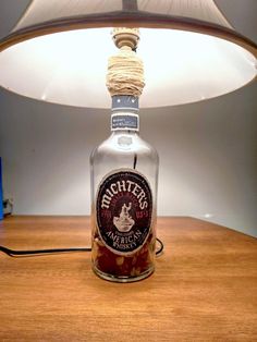 a lamp that is sitting on top of a table next to a bottle with a label on it