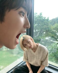 a woman sitting on a window sill with her mouth open next to another woman