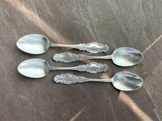 four silver spoons sitting on top of a stone table next to another set of three