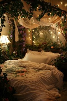 a bed covered in white sheets and pillows under a canopy with lights strung from the ceiling