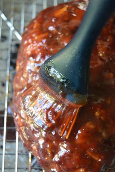 a spatula is being used to grate barbecue sauce on top of an uncooked meatball