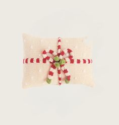 a knitted pillow with candy canes on it and a bow around the edge