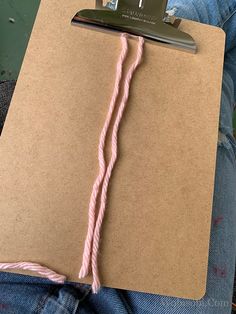 a piece of brown paper with pink string attached to it and a pair of scissors