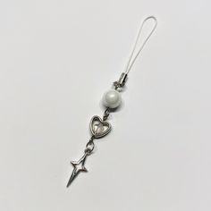 a pair of earrings with pearls and an arrow hanging from the end of each ear