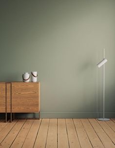 an empty room with green walls and two white bowls on a wooden table next to a lamp