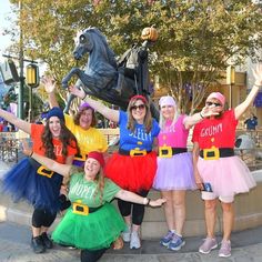 a group of people dressed up in costumes posing for a photo with a horse statue behind them