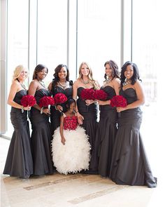 a group of women standing next to each other holding red and white flowers in their hands