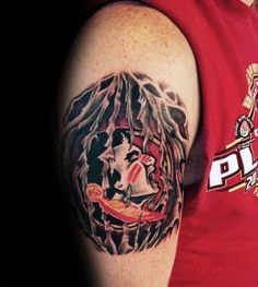 a man wearing a red shirt has a tattoo on his arm