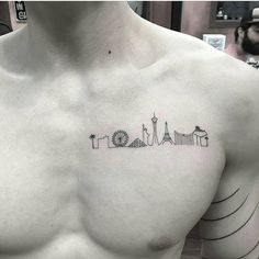 a man's chest with a small city skyline tattoo on the left side of his chest