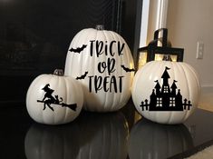 three white pumpkins with black lettering on them