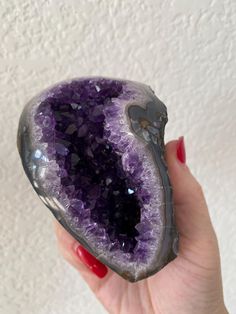 a woman holding a large purple rock with lots of crystals on it's surface