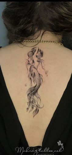 a woman's back with a fish tattoo on her upper and lower back neck