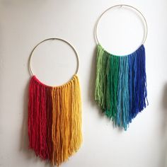 two hoop earrings with multicolored fringes hanging on the wall next to each other