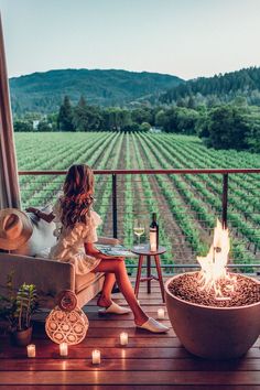 a woman sitting on a chair next to a fire pit with candles in front of her