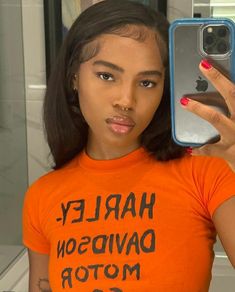 a woman taking a selfie in front of a mirror wearing an orange harley davidson t - shirt