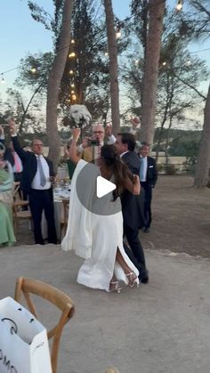 a bride and groom are dancing at their wedding reception in the evening with guests watching