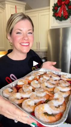 a woman holding a tray of doughnuts in her kitchen