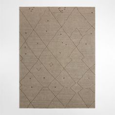 a beige rug with an abstract design on the bottom and sides, in front of a white wall