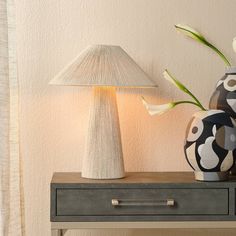 two vases with flowers on a table next to a lamp