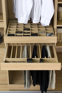 an organized closet with clothes hanging on wooden shelves and shoes in bins underneath them