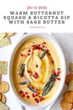 a white bowl filled with hummus, spinach and carrot dip surrounded by crackers