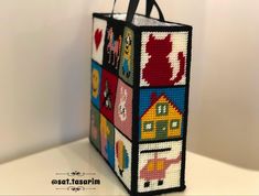 a handbag made out of squares and pictures on it's front, sitting on top of a table