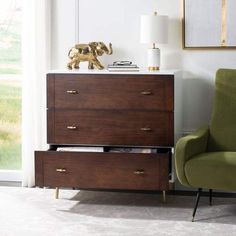 a green chair sitting in front of a dresser next to an elephant figurine